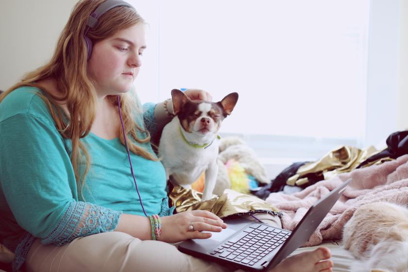 Person sitting with laptop and dog next to them. By Alexander Grey on Unsplash
