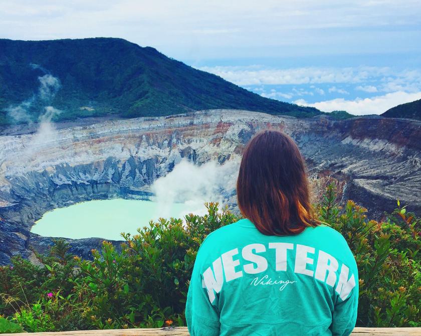 Student wearing a green WESTERN shirt looking at the Poás Volcano in Costa Rica