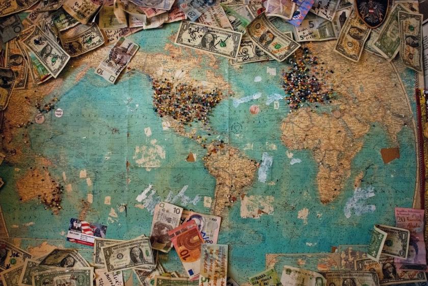 Image of a world map and money on pinned to it.