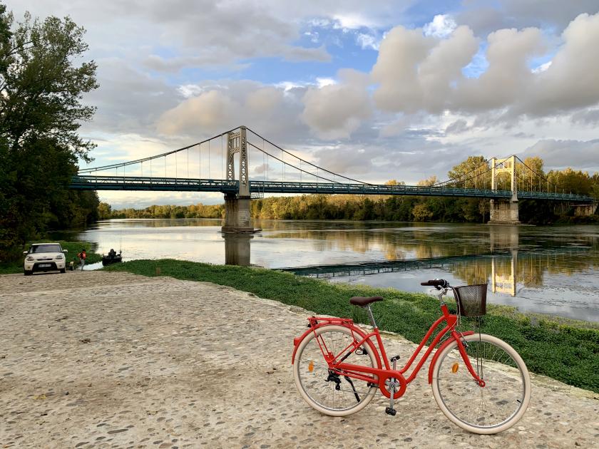 Auvillar Bridge in France with a red bicycle in front of the water. 